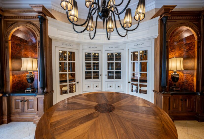 Rounded cabinets leading to the scullery, fine wine and pantry areas, with a large round table 