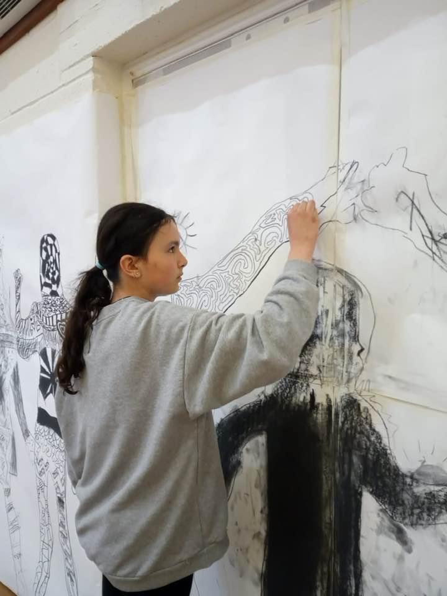 Pupil Maisie fills in part of her silhouette near where it connects to a classmate's at Big Draw 2022