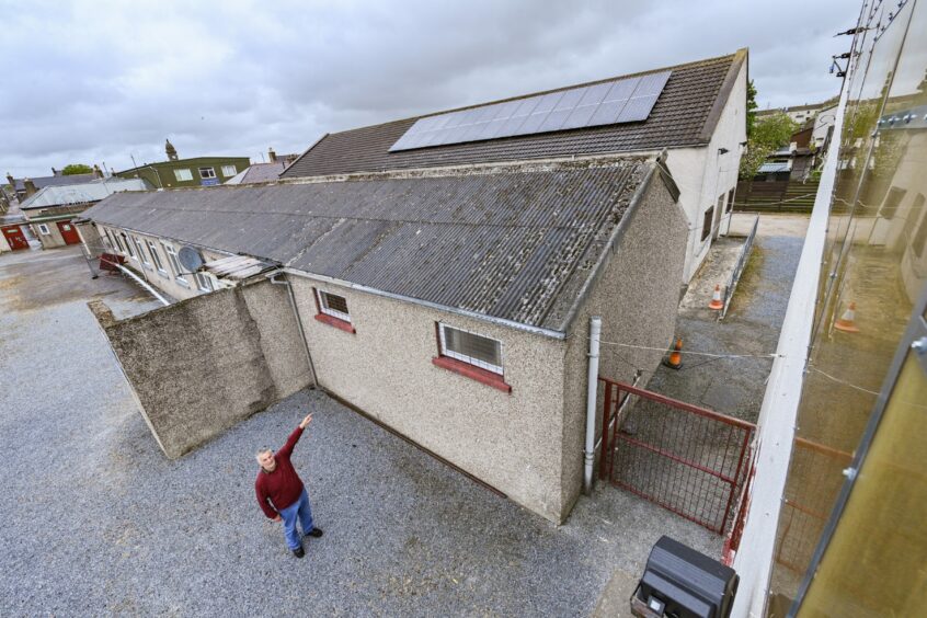 Keith FC Andy Troup points at the roof where the solar panels are installed.