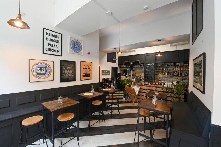 Quirky decor in the Faffless bar including a black and white striped floor, wooden palette bar and colourful framed prints