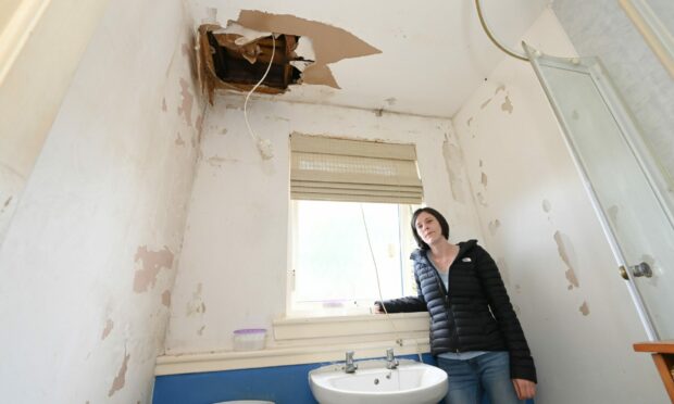 Anne Paton's daughter shows where the ceiling collapsed in the bathroom after being flooded with sewage. Picture by Kenny Elrick.