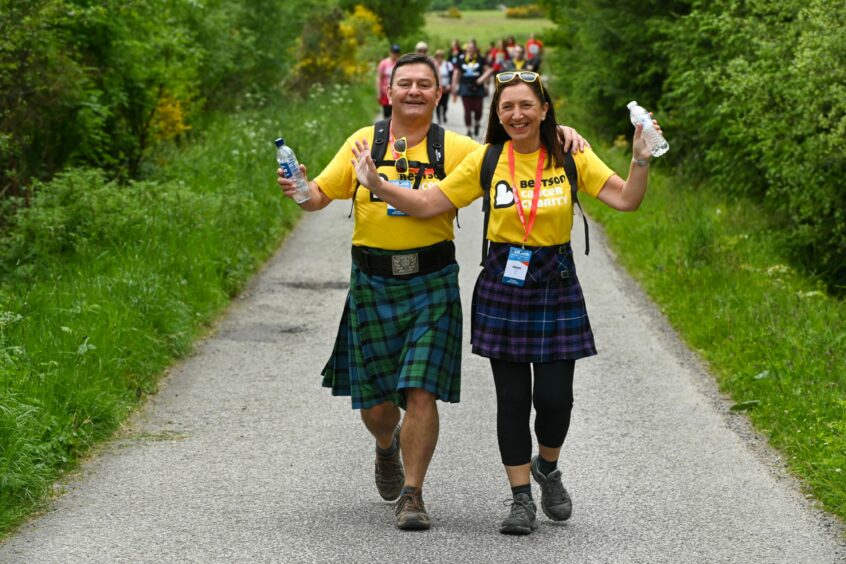 A man and woman dressed in kilts and yellow charity t-shirts on the Kiltwalk 