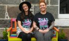 Laurs Mears-Meynolds and Dawn Farmer sitting next to each other on a rainbow coloured bench in Fittie