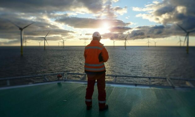 Worker looks out at offshore windfarm from a deck