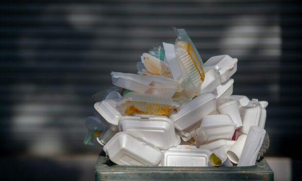 A pile of plastic take-away boxes overflowing from a bin.