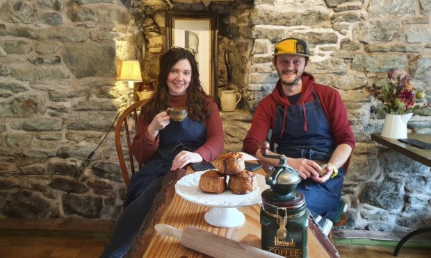 Rachel and Drew Hardiman sitting at a table in their cafe. A plate with three scones in front of them.