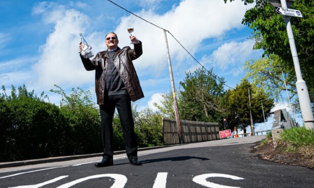 Fordoun resident Alex Wasinowicz celebrated the potholes being fixed with a bottle of bubbly. Photograph by Wullie Marr, 11/05/22