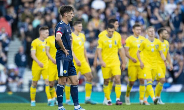 Aaron Hickey watches on as Ukraine celebrate opening the scoring at Hampden Park.