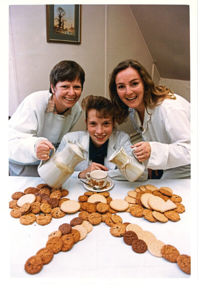 Simmers staff with biscuits in a Macmillan cancer logo shape ahead of a charity coffee morning in1993