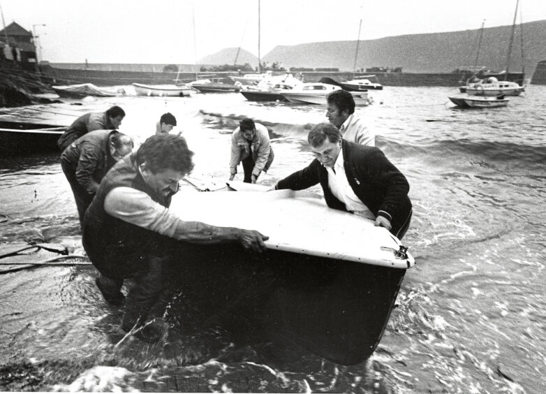 Huge waves batter Stonehaven harbour and a group of men help a small boat clear of danger in 1987