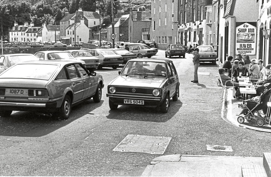 Cars drive down the front of Stonehaven harbour on a Saturday in 1982