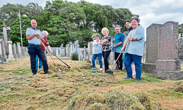 Friends of Ellon Cemetery standing with cut grass next to the graves