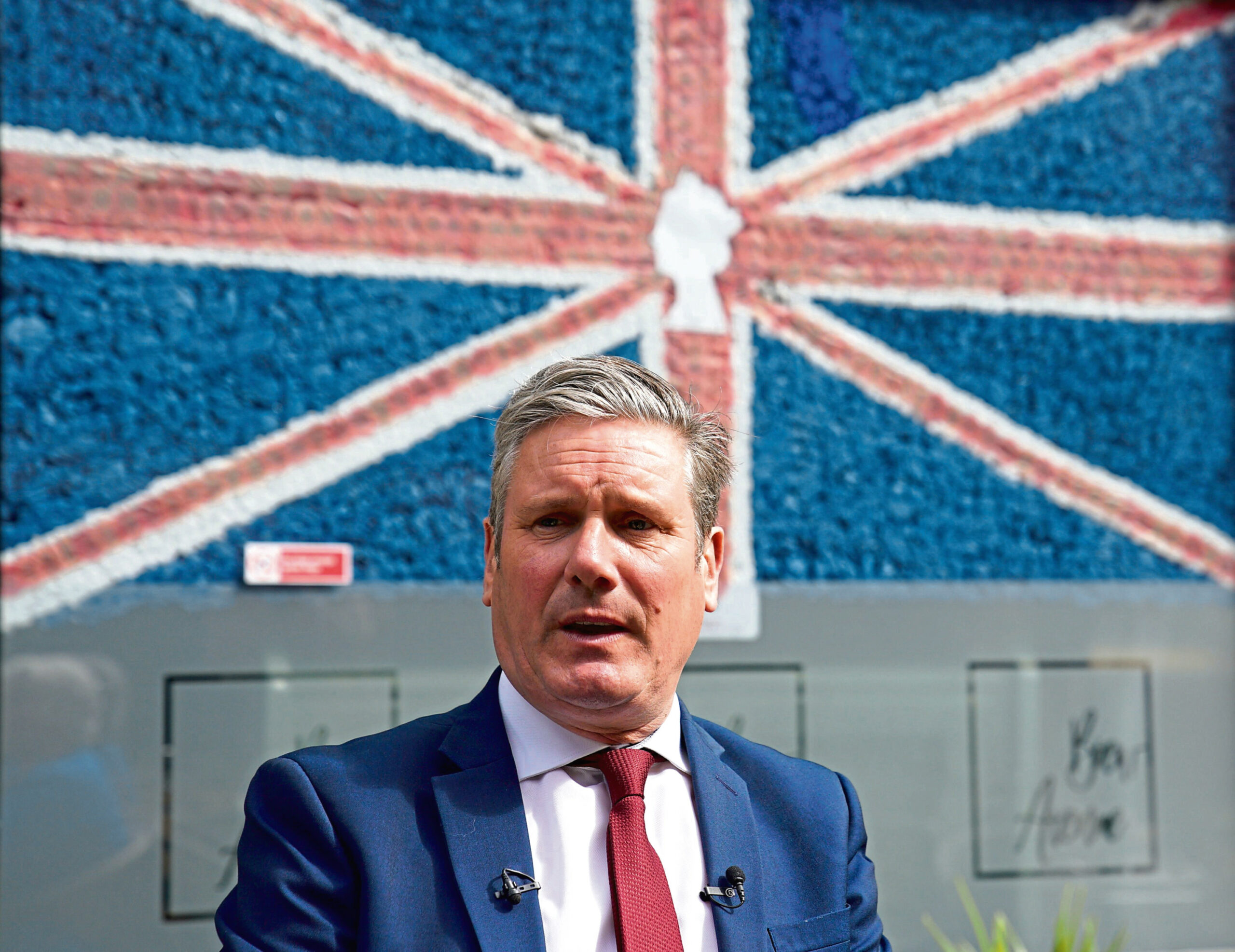 Keir Starmer in front of a union flag with Queen Elizabeth II's silhouette on it