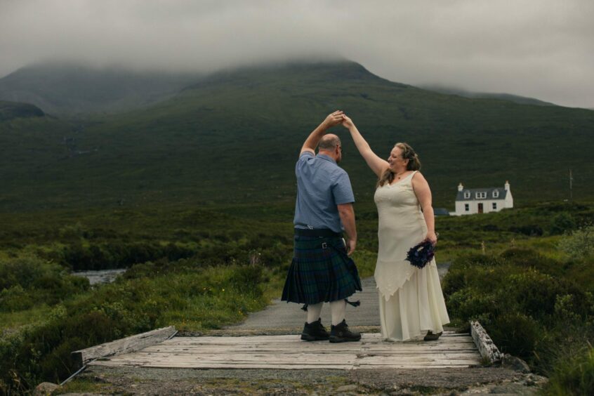 Amanda and Paul with the atmospheric hills of Skye behind them during the ceremony.