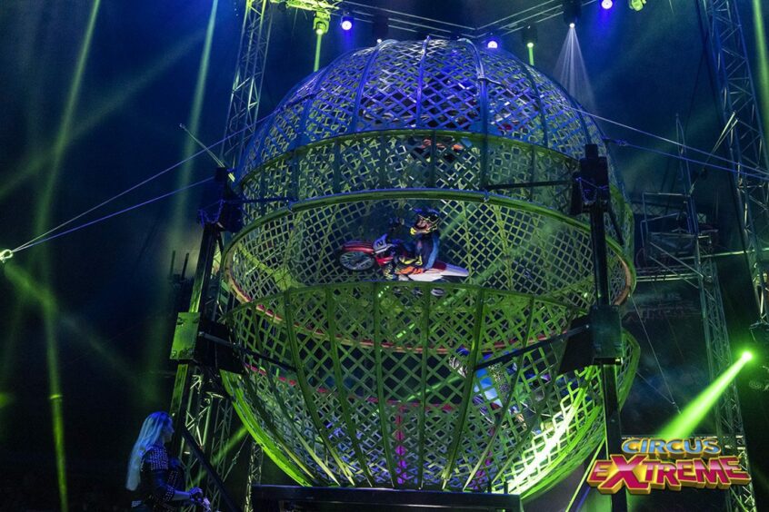 pilot rides motorcycle inside a giant spehere in Circus Extreme