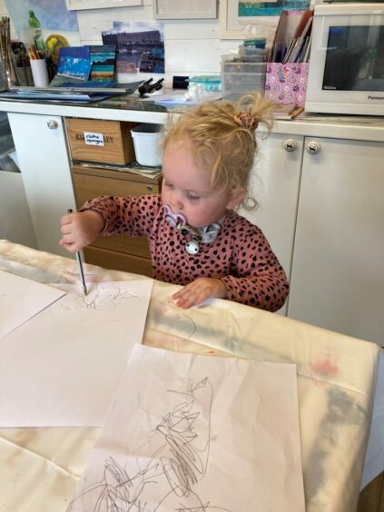 Edith drawing at the kitchen table
