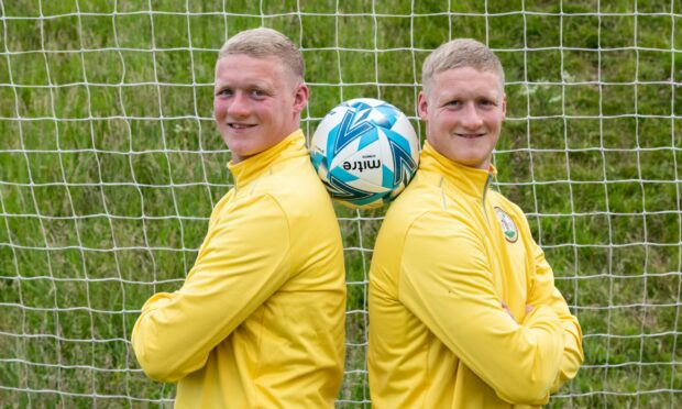Lee Fraser, left, and twin brother Graham standing back to back with a football between them