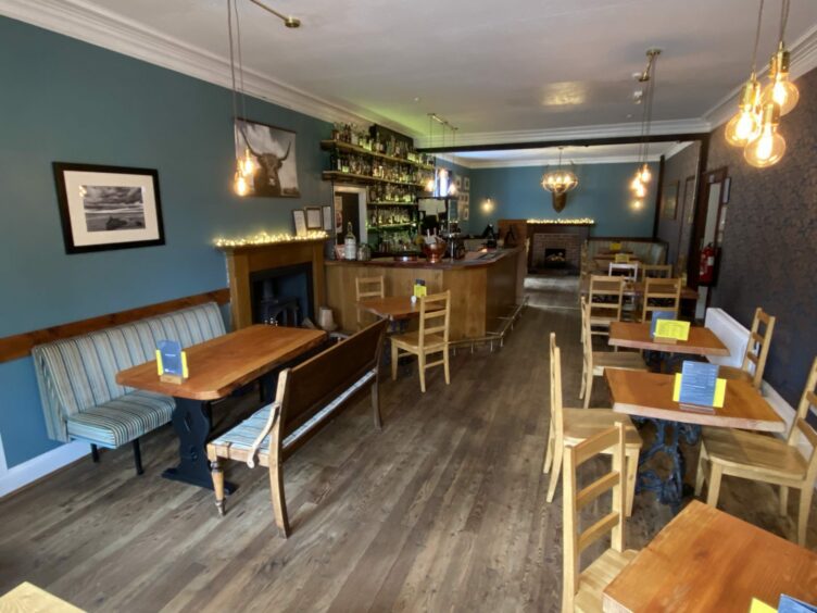 The inside of the Stag restaurant and bar, which is also part of Kinlochewe Hotel. The room is painted blue with, rustic solid wood tables and bar.