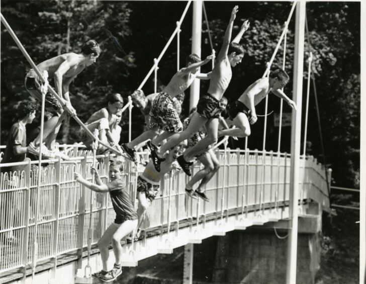 Inverness children leaping from the 30ft Generals Well suspension bridge over the River Ness into shallow water