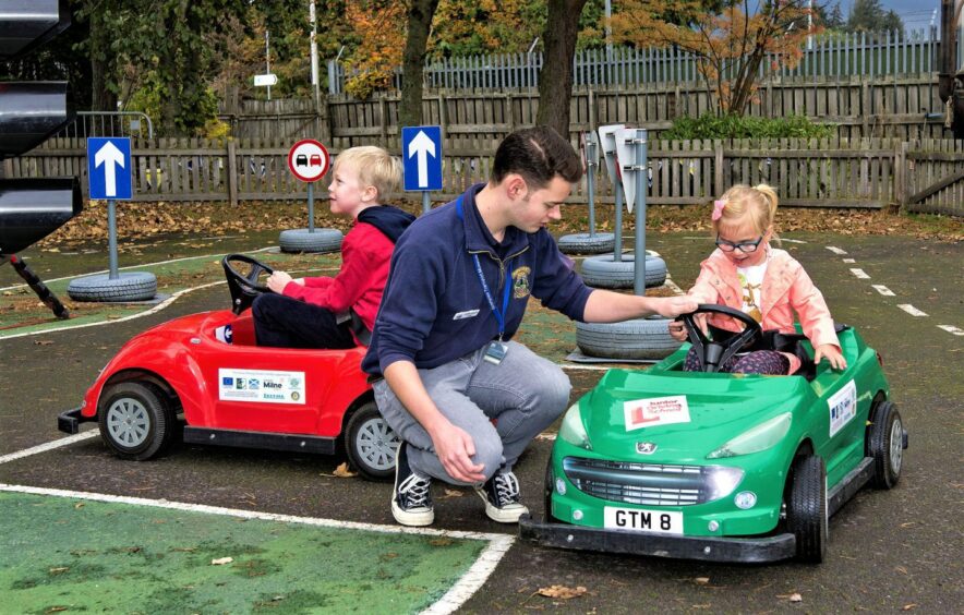 Children driving the mini cars with the help of an instructor.