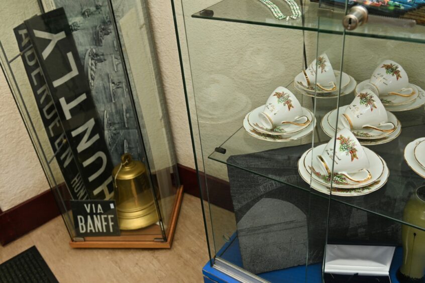 Antique bus signs in a glass case next to another glass case full of antique china teacups and saucers