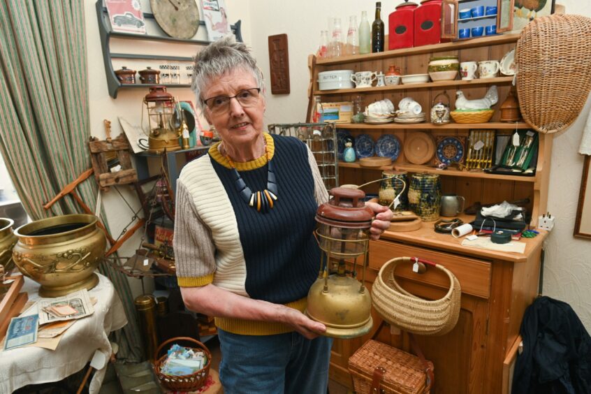 Alison Milne in her shop, holding an antique lantern