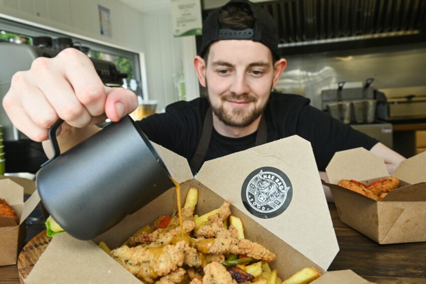 Danny Grant pouring sauce over a to-go container of food