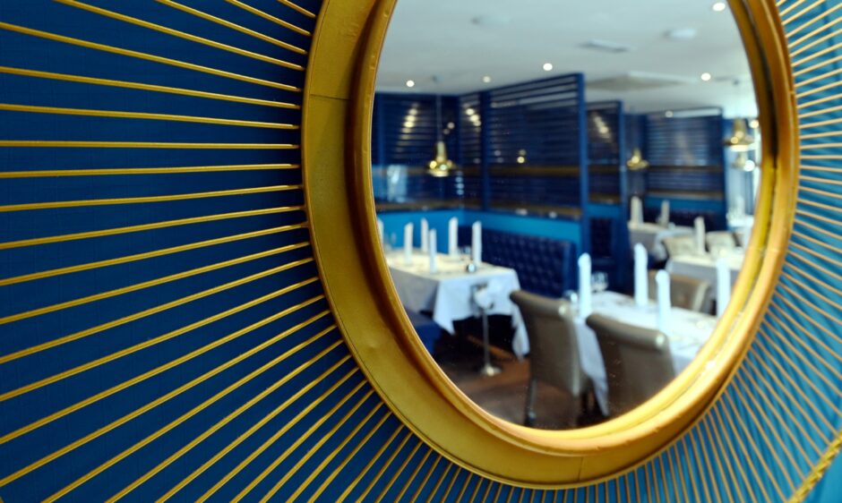 A gold-rimmed, round mirror in Echt Tandoori reflecting the rest of the restaurant