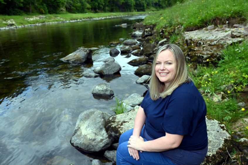 Louise Lang sitting on stone next to river in Banchory