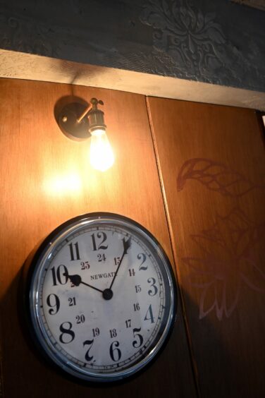 A clock under a wall light inside Frogmoon Cafe.