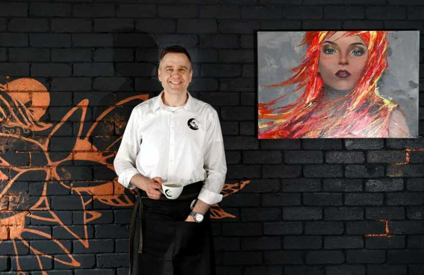 Owner Adam Maksymiuk alongside one of the cafe's bold prints.
