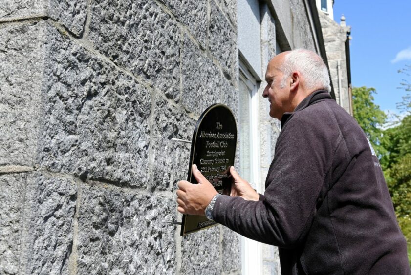 Sign Express installer George Hamilton fixing up the Aberdeen FC plaque on the Chanonry building. 