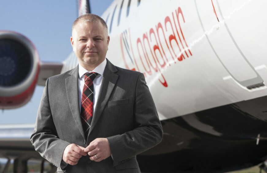 Loganair chief executive Jonathan Hinkles standing in front of one of the airline's aircraft, with its logo visible. 