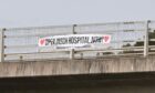 A Save Insch Hospital banner which has been hung from an overpass on the A96 near Kintore.