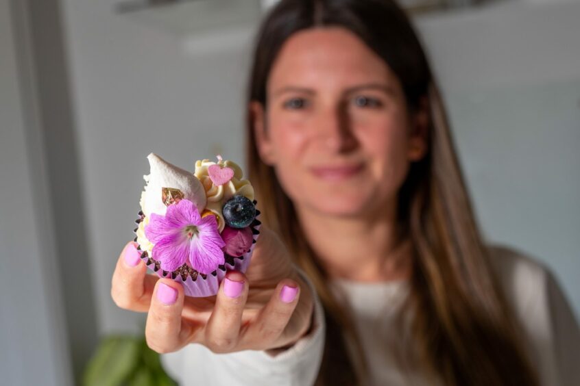 Jemma Mathieson holding one of her decorated cupcakes.