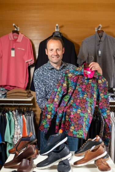 Mark holding up one of the store's bolder printed shirts.