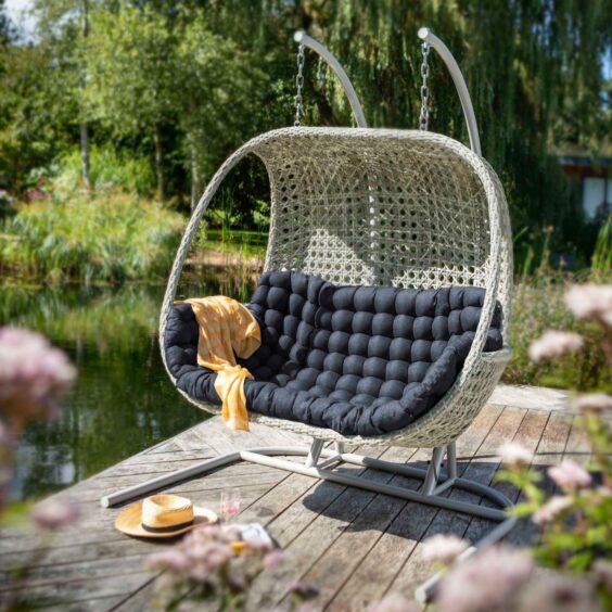 An outdoor swinging chair on a pond-side patio.