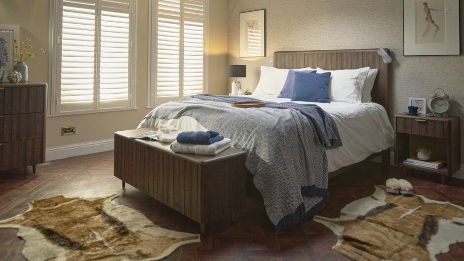 A bed with a matching ottoman and two faux animal skin rugs