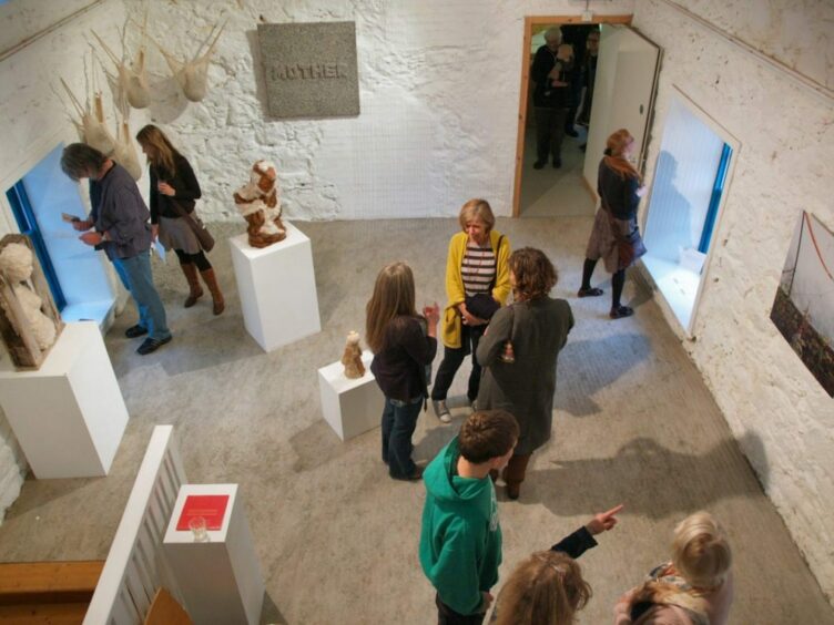 Visitors look at art in a gallery space.