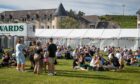 Groups of people sitting on the grass in front of a white gazebo during the Midsummer Beer Happening