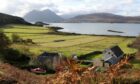 View of Isle of Skye with fields, water and mountain in background.