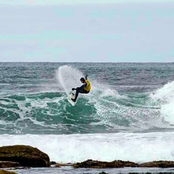 A photograph of Iain surfing waves on the sea