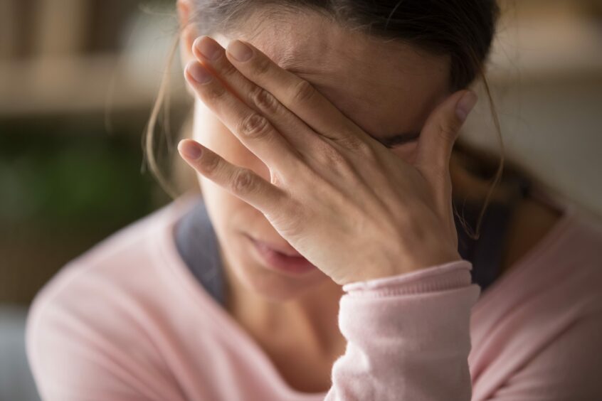 Sad tired young woman touching forehead with headache, migraine or depression, frustrated upset girl worried about problem, feeling stressed and covering face crying with hand, suffering from sorrow and pain concept;