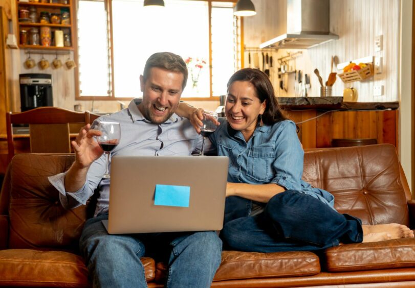 Couple enjoying lockdown drinks with family and friends online.