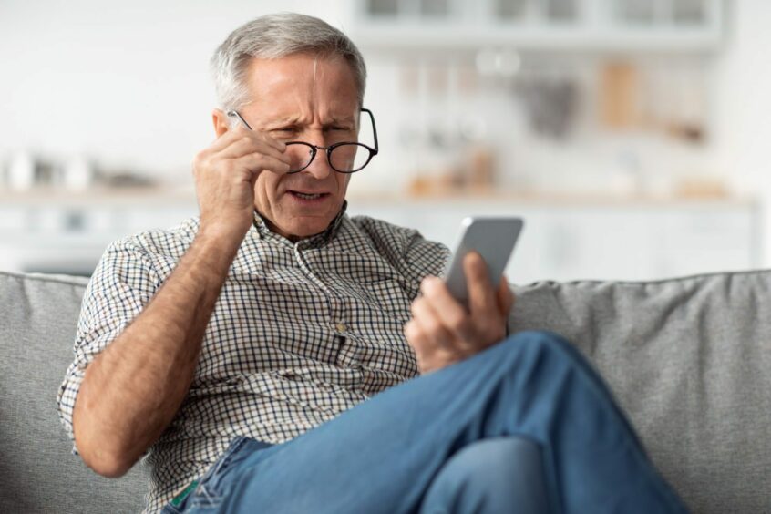 Old man squinting with his glasses on trying to read what's on his iphone