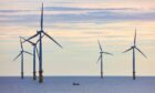 A small fishing boat dwarfed by huge wind turbines in the North Sea.. Image: Shutterstock