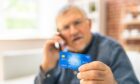 Pensioner holding a bank card in his hand
