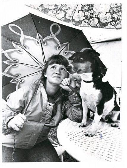 A girl and her dog under an umbrella at the echt show.