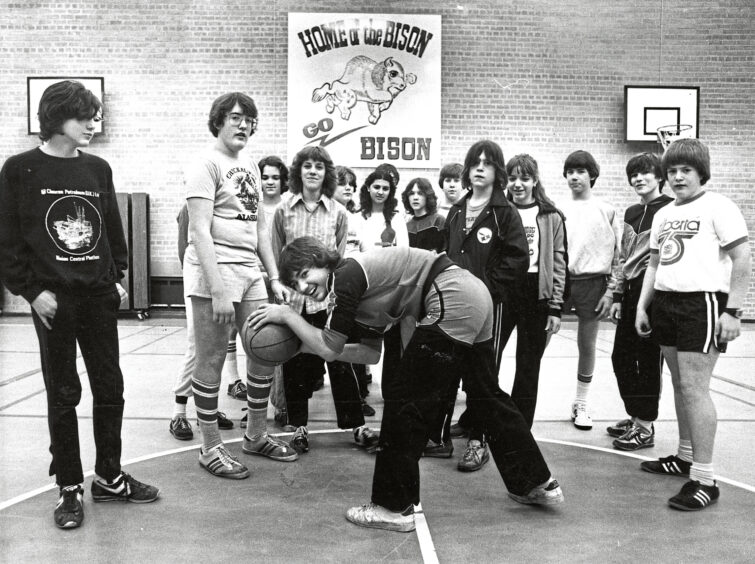 Basketball practice in the gymnasium with, in the background, a poster of the bison, the indigenous American animal which is the school's mascot. 1982 Aberdeen American School