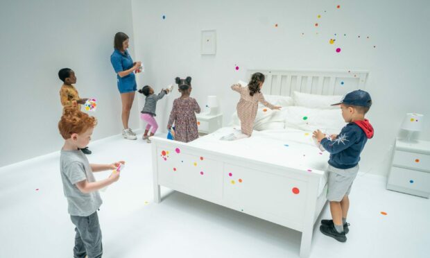 Children apply the first stickers to Yayoi Kusama's interactive work The obliteration room at the Tate Modern in London. Aaron Chown/PA Wire